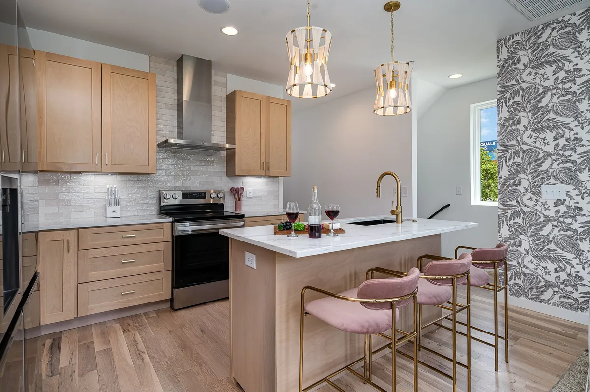 A contemporary kitchen interior with a large island, pendant lighting, and stainless steel appliances. The layout is perfect for cooking, entertaining, and socializing, with plenty of space for group gatherings.