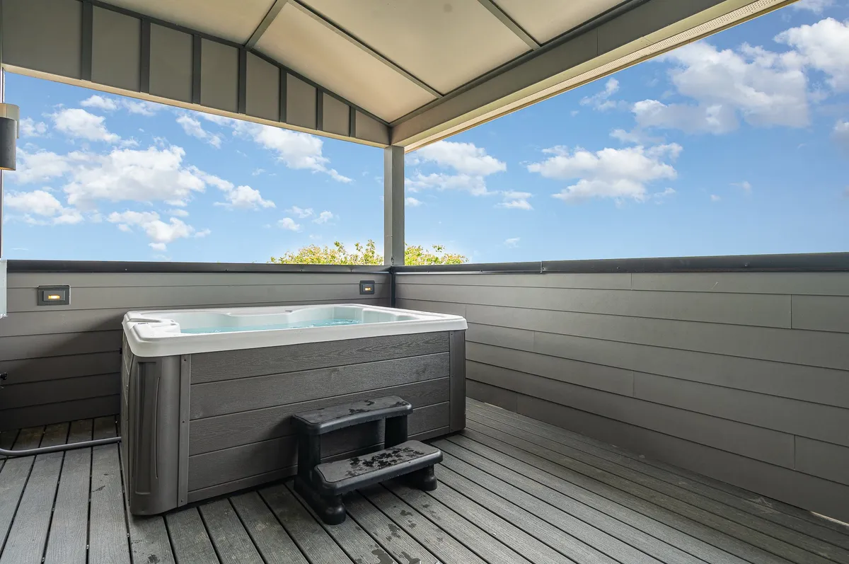 A tranquil hot tub sits on the deck with a clear view of the sky, inviting guests to relax and enjoy stargazing or a peaceful morning coffee. The ambiance is intimate and serene, perfect for private group moments.