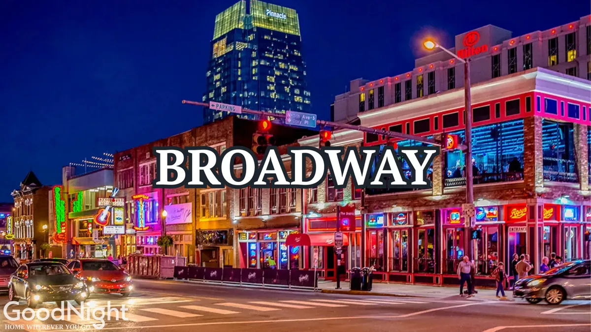 A bustling Nashville street at night, lit by vibrant neon signs and full of people enjoying the lively nightlife. The sidewalks are crowded and high-rise buildings frame the energetic scene, encapsulating the heart of Broadway's famous music and honky-tonk destinations.